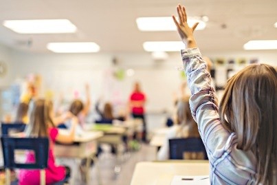 child raising hand in classroom