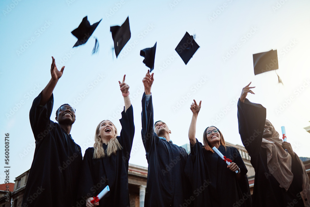 students thowing graduation caps