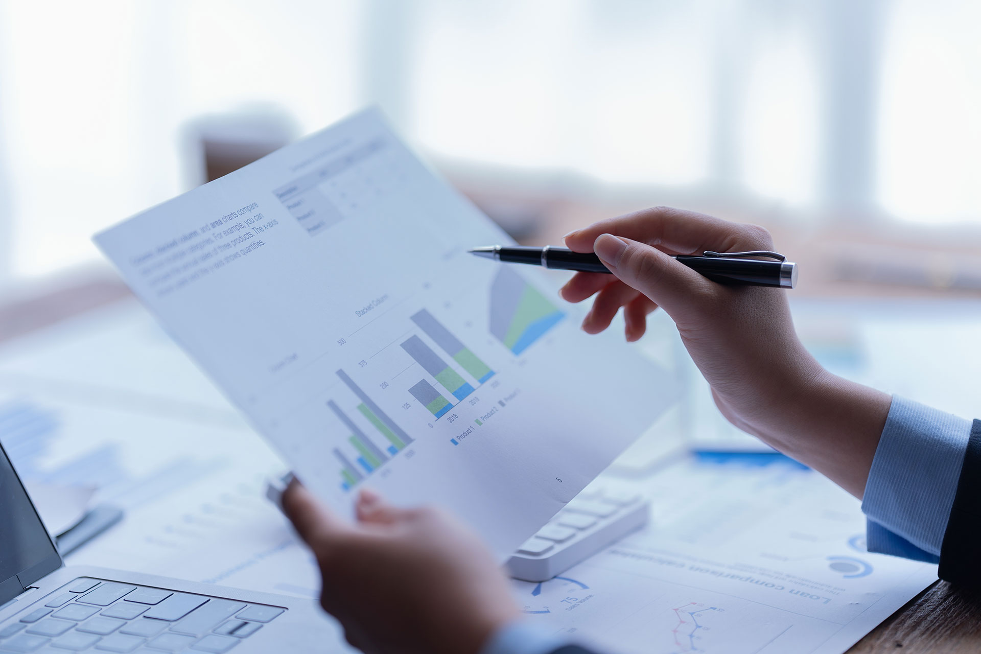 hands holding pen and paper with graphs