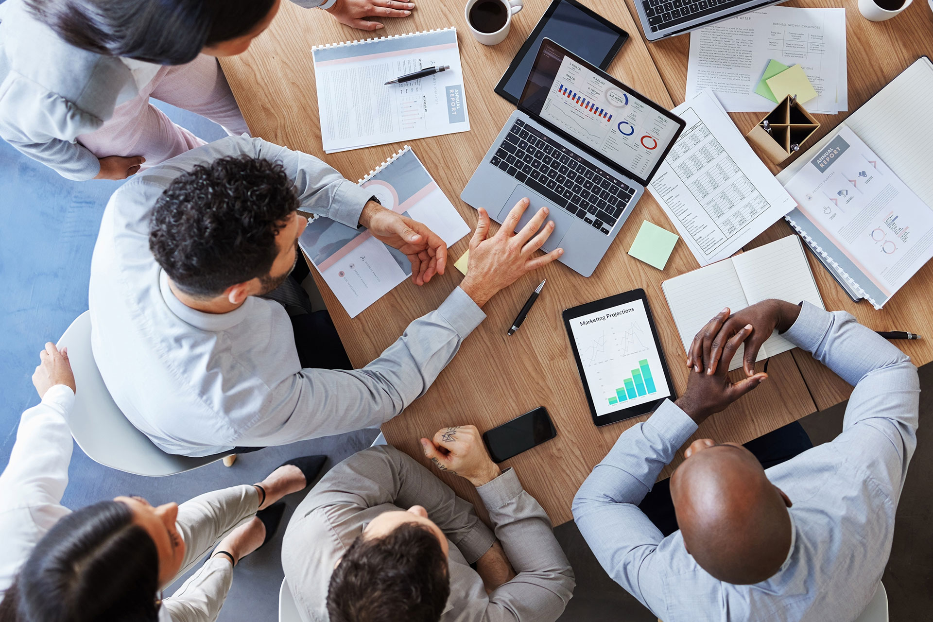 group of buisnessmen around laptop, paperwork, graphs